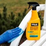 Osoba czyści białą powierzchnię sprayem do plastiku i mebli ogrodowych marki ERLA, używając niebieskiej ściereczki.