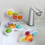 Zabawki spinner do wody dla dzieci, kolorowe i edukacyjne, przymocowane do wanny obok kranu z bieżącą wodą.