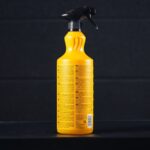 Żółta butelka sprayu do czyszczenia z czarnym aplikatorem na ciemnym tle, pojemność 1L.