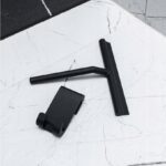 Czarny czyścik do szyb z uchwytem na białej marmurowej powierzchni, widok z góry.