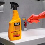 Spray czyszczący ERLA Saniz Shine i ręka w rękawiczce polerująca kran w łazience.