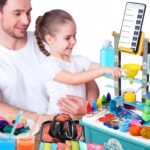 Dziecko z dorosłym bawią się zestawem do eksperymentów naukowych, tworząc kolorową wulkaniczną erupcję.