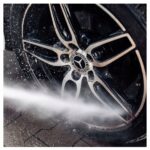 Czyszczenie felgi samochodowej myjką wysokociśnieniową; połysk metalicznego koła po umyciu.