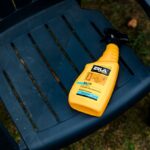 Środek czyszczący w żółtej butelce na plastikowym krześle ogrodowym, produkt do pielęgnacji mebli.