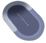 Niebieski dywanik kąpielowy o opływowym kształcie z napisem BATHROOM na środku. Idealny do łazienki.