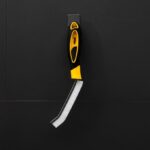 Żółta szczotka do fug na czarnej ścianie, idealna do dokładnego czyszczenia płytek i trudno dostępnych miejsc.